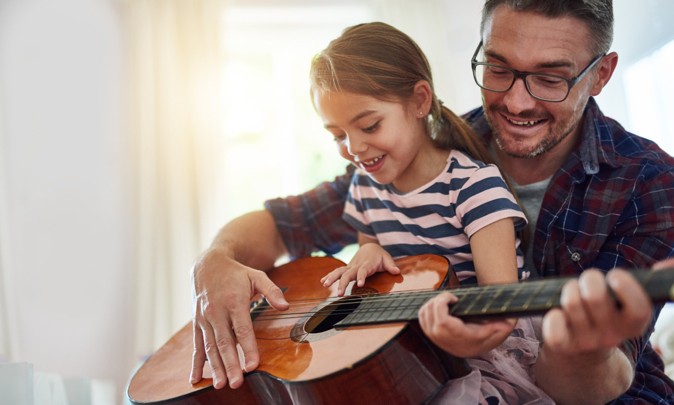 A father and daughter play the guitar happily